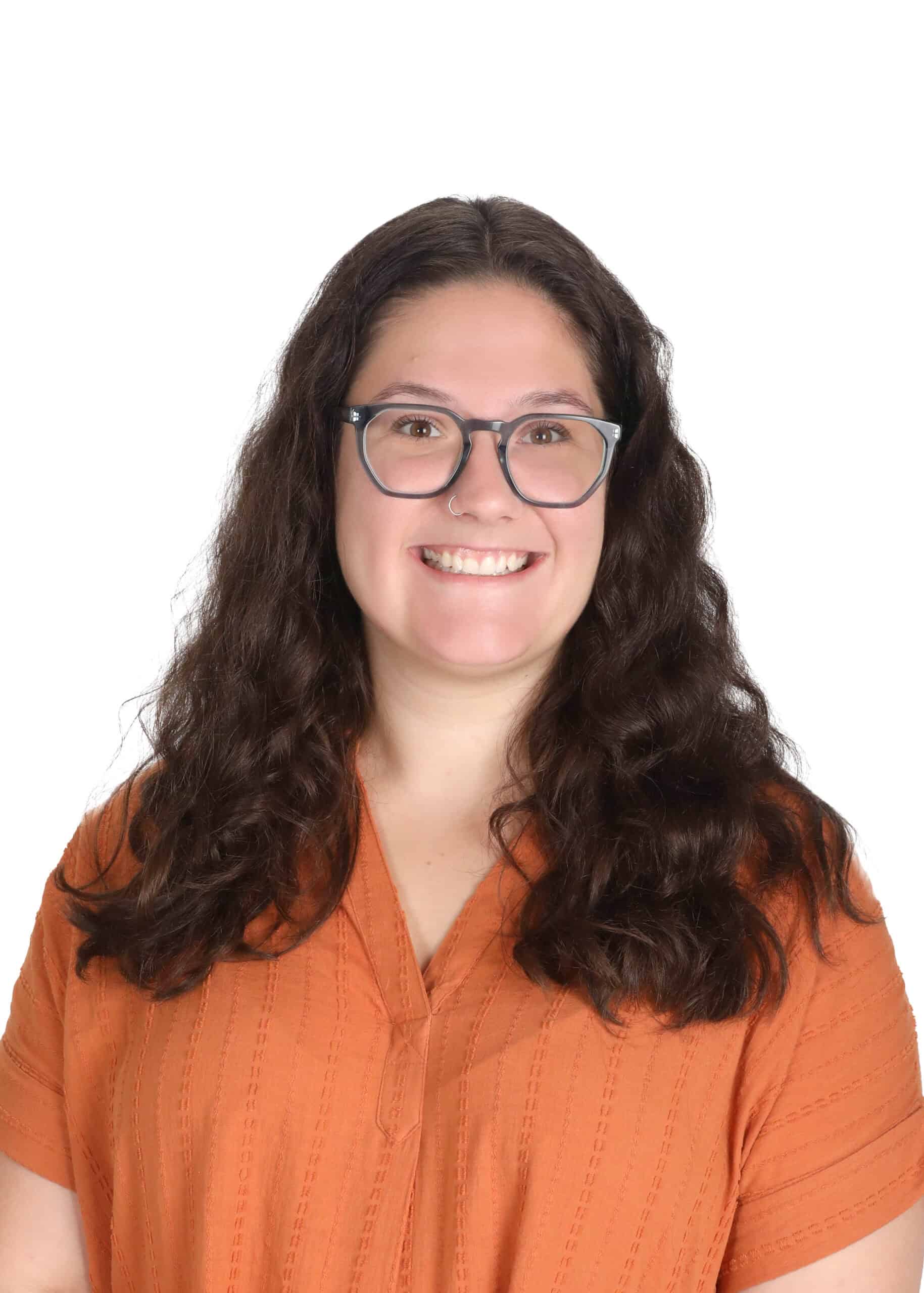 Portrait of Madison Reichel, smiling woman with glasses and long curly hair, wearing an orange shirt.