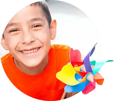 Smiling boy holding colorful pinwheel at The Center for Children with Special Needs.